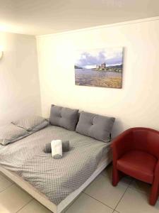 a bed with a red chair and a picture on the wall at Studio SCOTTLAND in Chambéry