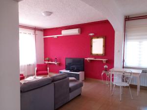 a living room with a couch and a red wall at Apartman Sara in Pula