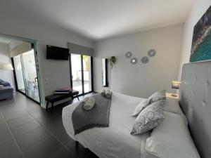 ein Schlafzimmer mit einem weißen Bett und einem Fernseher in der Unterkunft Suite Dreams Fuerteventura in Villaverde