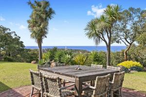 a wooden table and chairs with the ocean in the background at Bimbadeen Luxurious Retreat in Aireys Inlet