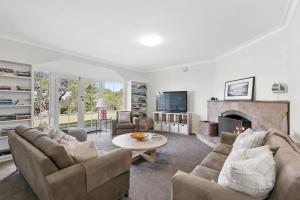 a living room with two couches and a fireplace at Bimbadeen Luxurious Retreat in Aireys Inlet