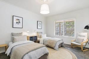 a bedroom with two beds and a chair and a window at Bimbadeen Luxurious Retreat in Aireys Inlet +4 photos
