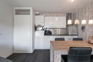 a kitchen with white cabinets and a wooden table at Beach Appartement 14 - Aan de duinen, Callantsoog aan Zee in Callantsoog +24 photos