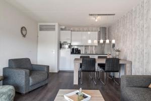 a living room with a table and chairs and a kitchen at Beach Appartement 14 - Aan de duinen, Callantsoog aan Zee in Callantsoog