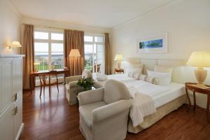 a large white bedroom with a large bed and chairs at Sunday Schwielowsee Resort - Hotel in Werder +83 photos