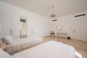 a white bedroom with two beds and a table at VESTA - El Gouna Residence in Hurghada