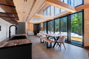 a kitchen and dining room with a table and some windows at Chillwood - Sauna & Cold Plunge - Hammock Beds in Notre-Dame-de-la-Merci
