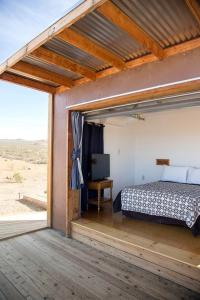 ein Schlafzimmer mit einem Bett auf einer Holzterrasse in der Unterkunft Secluded Glamping Eco-Pod Rental in the Mojave Desert near Ridgecrest, California in Ridgecrest