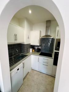a kitchen with white cabinets and an archway at Beautiful apartment, moments from the sea in Weymouth