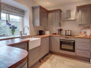 una cucina con mobili in legno e un lavello di Tiesel & Truffles Cottages a Cheltenham