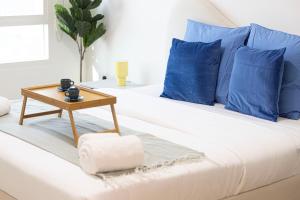 a white bed with blue pillows and a table on it at Prime Location - 2BR with Spectacular Sea View in Dubai