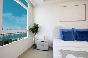 a bedroom with a window and a bed with blue pillows at Prime Location - 2BR with Spectacular Sea View in Dubai