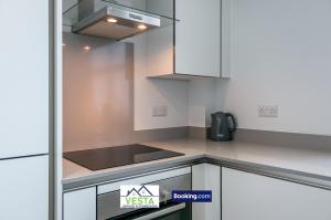 a kitchen with white cabinets and a stove top oven at Executive Apartment Close to Station in Hatfield