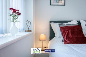 a bedroom with a bed with a vase with flowers in it at Executive Apartment Close to Station in Hatfield