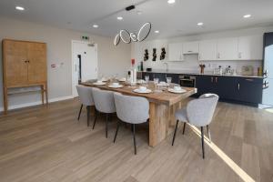 a kitchen with a large wooden table and chairs at Luxury 2 Bedroom with Gym, Workspace, Balcony, Free Parking and 3 mins walk to train station in Walton-on-Thames