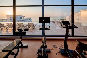 a gym with exercise bikes in front of a large window at Tropicana - Infinity Pool & Spa Resort in Mamaia Nord
