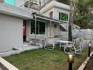 a group of chairs and a table in a yard at The Hermitage Cottage-Exclusive Mountain Escape in Murree