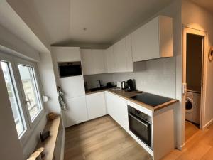 a small kitchen with white cabinets and a stove at Appartement Le POULIGUEN in Le Pouliguen +2 photos