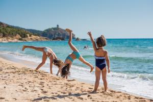three girls playing in the sand on the beach at Chia Laguna - Hotel Village in Chia