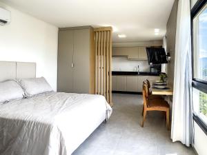 a bedroom with a bed and a table and a kitchen at Apto com Piscina / até 3 pessoas in Limeiro