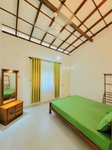 1 dormitorio con cama verde y espejo en Serene Lush Holiday Home, en Tangalle