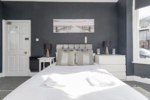 a bedroom with a large white bed with black walls at NEW! Central Studio, Free Parking, WiFi, 5 Min to Train Station in Spon End