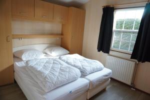 a bedroom with a bed with white sheets and a window at Kustverhuur, Groede Paarlhof 45 in Groede