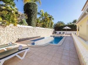 een achtertuin met een zwembad en een stenen muur bij Casa Camarinha in Carvoeiro