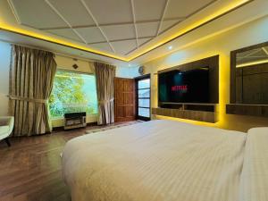 a bedroom with a large bed and a flat screen tv at The Hermitage Cottage-Exclusive Mountain Escape in Murree +35 photos