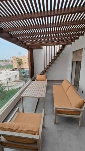 a balcony with a wooden pergola and two benches at Cocon moderne in Essaouira +1 photo
