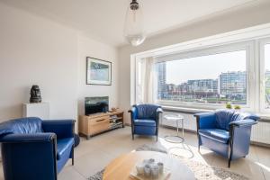 sala de estar con sillas azules y ventana en View of the yacht port, en Ostende