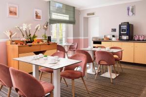 a dining room with tables and chairs and a kitchen at Best Western Hotel Lakmi Nice in Nice