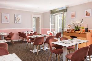 a dining room with tables and chairs and pink walls at Best Western Hotel Lakmi Nice in Nice