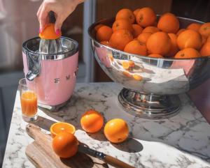 a person is juicing oranges on a table with a bowl of oranges at Best Western Hotel Lakmi Nice in Nice