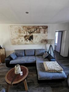 a living room with a blue couch and a deer painting at Le Cocon de Litia in Cornimont +29 photos