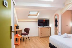 a bedroom with a bed and a tv and a chair at Best Western Hotel Lakmi Nice in Nice