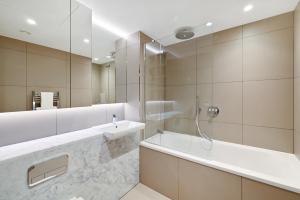 a bathroom with a tub and a sink and a mirror at Access Tower Hill in London +45 photos