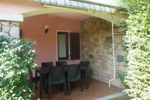 Un patio con mesa y sillas y un muro de piedra. en Vacanze a Villa Ortensia, en San Teodoro