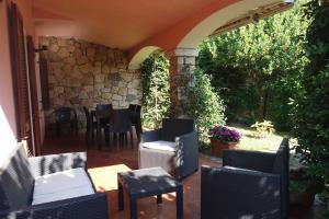 un patio con sillas, mesas y una pared de piedra. en Vacanze a Villa Ortensia, en San Teodoro