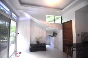 a hallway with white walls and a staircase with a window at Aguada Hills Residence in Puerto Galera
