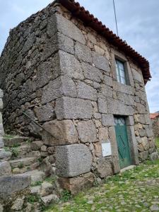 an old stone building with a green door at Casa de Aldeia Vale do Mondego in Guarda