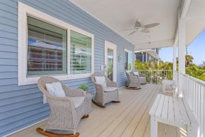 a porch with chairs and a table and a ceiling fan at Welcome to Mermaid Bay Vacation Rental - 261 Delmar home in Fort Myers Beach