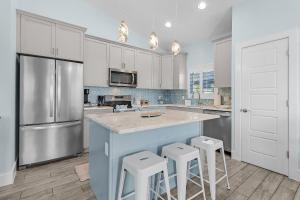 a kitchen with white cabinets and a blue island with stools at Welcome to Mermaid Bay Vacation Rental - 261 Delmar home in Fort Myers Beach