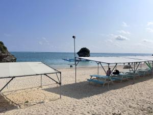 a group of people sitting on a beach with umbrellas at ビーチサイドペンションみーばる in Nanjo