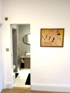 a bathroom with a white wall with a painting on it at Studio flat in Fitzrovia in London +2 photos