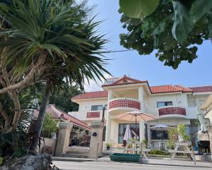 a large building with a palm tree in front of it at ビーチサイドペンションみーばる in Nanjo
