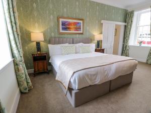 a bedroom with a large bed with green wallpaper at Royal Artillery Cottage - Culzean Castle in Maybole