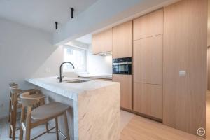 a kitchen with wooden cabinets and a counter with stools at Stylish apartment in Knokke - Balcony city view in Knokke-Heist