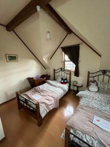 a attic room with three beds and a window at アンティークス岐阜関 Antiques Gifu Seki in Sekimachi