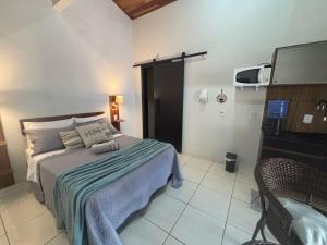 a bedroom with a bed with a television and a chair at Privacidade, WiFi, Microondas, Prime Vídeo, Alexa in Chapada dos Guimarães